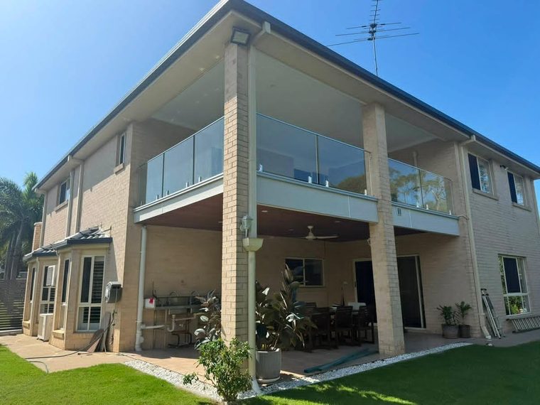 Repaired second-storey balcony with a new glass balustrade on a rendered home