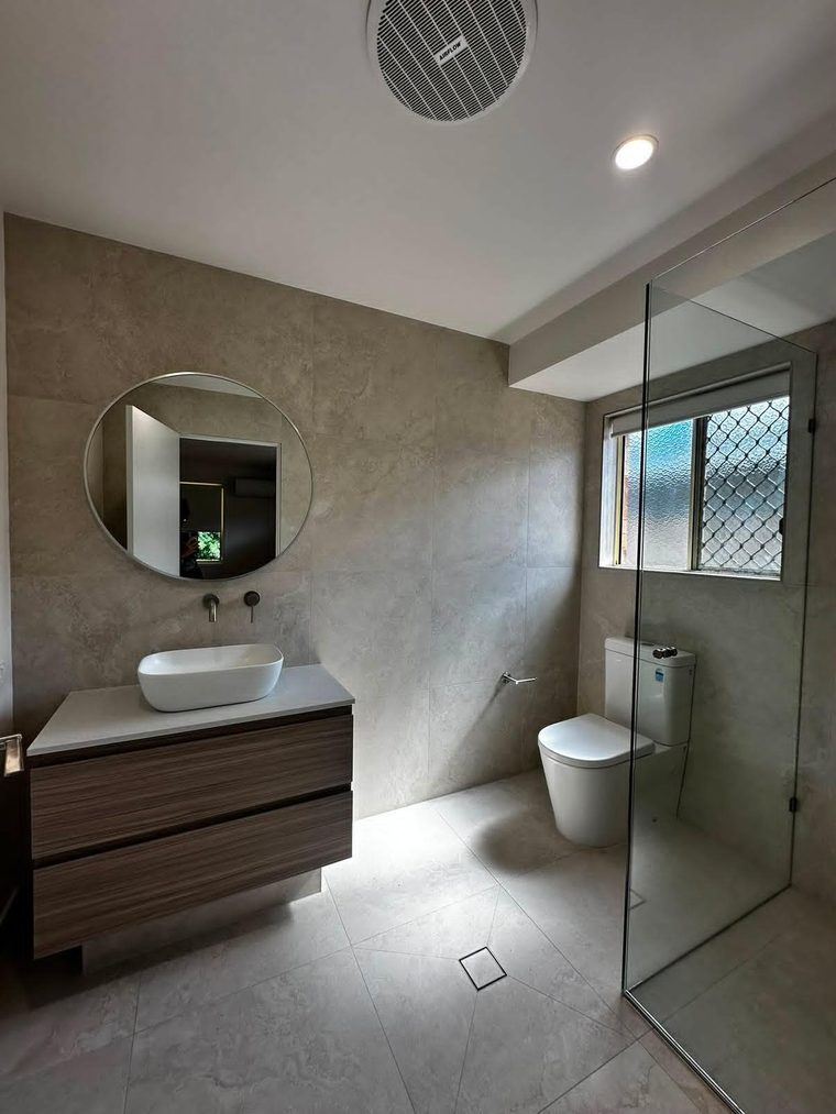 Bathroom with a square-set ceiling, round mirror and timber vanity