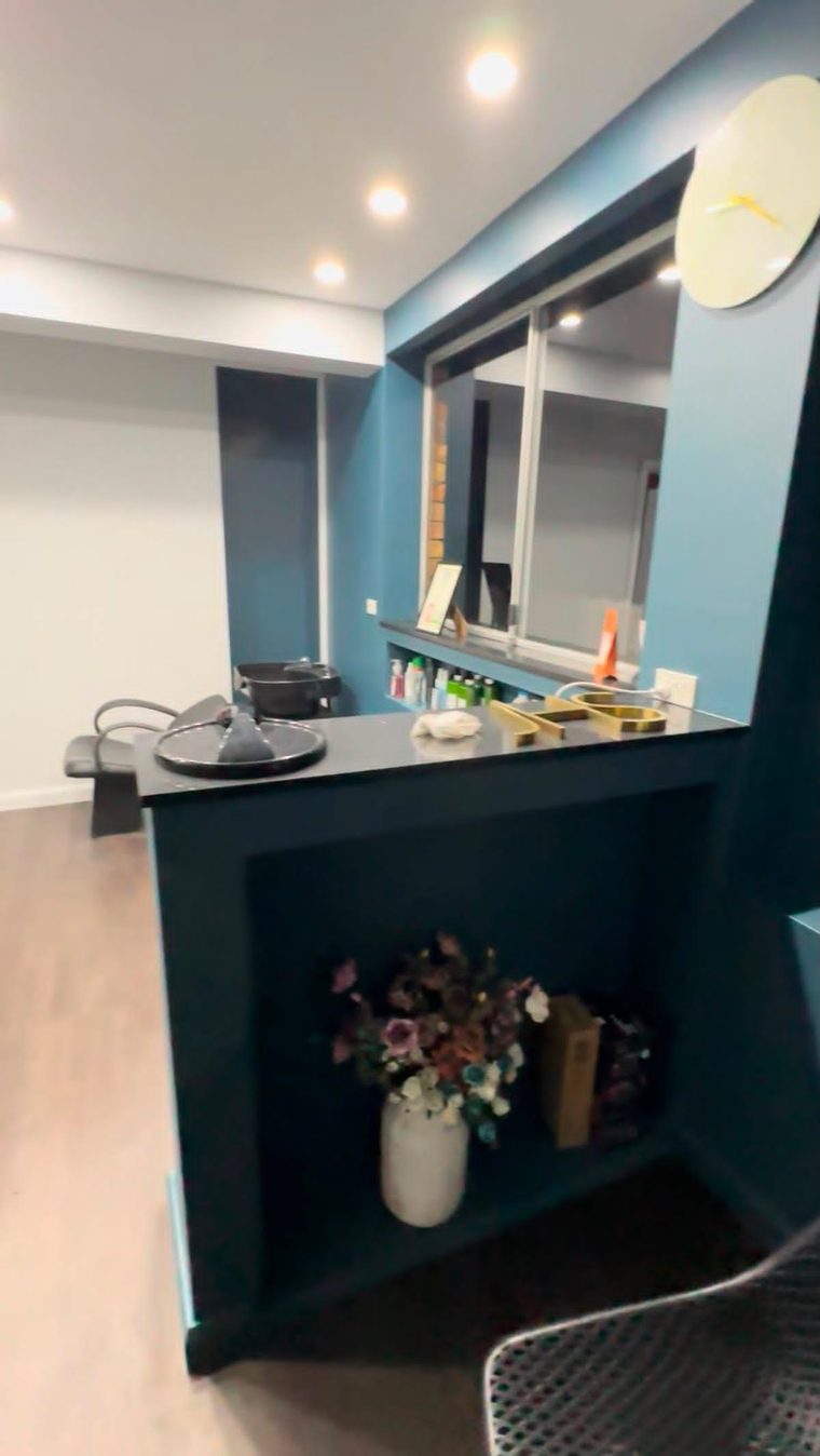 Same garage converted into a bar and living space with custom teal cabinetry and a servery bench